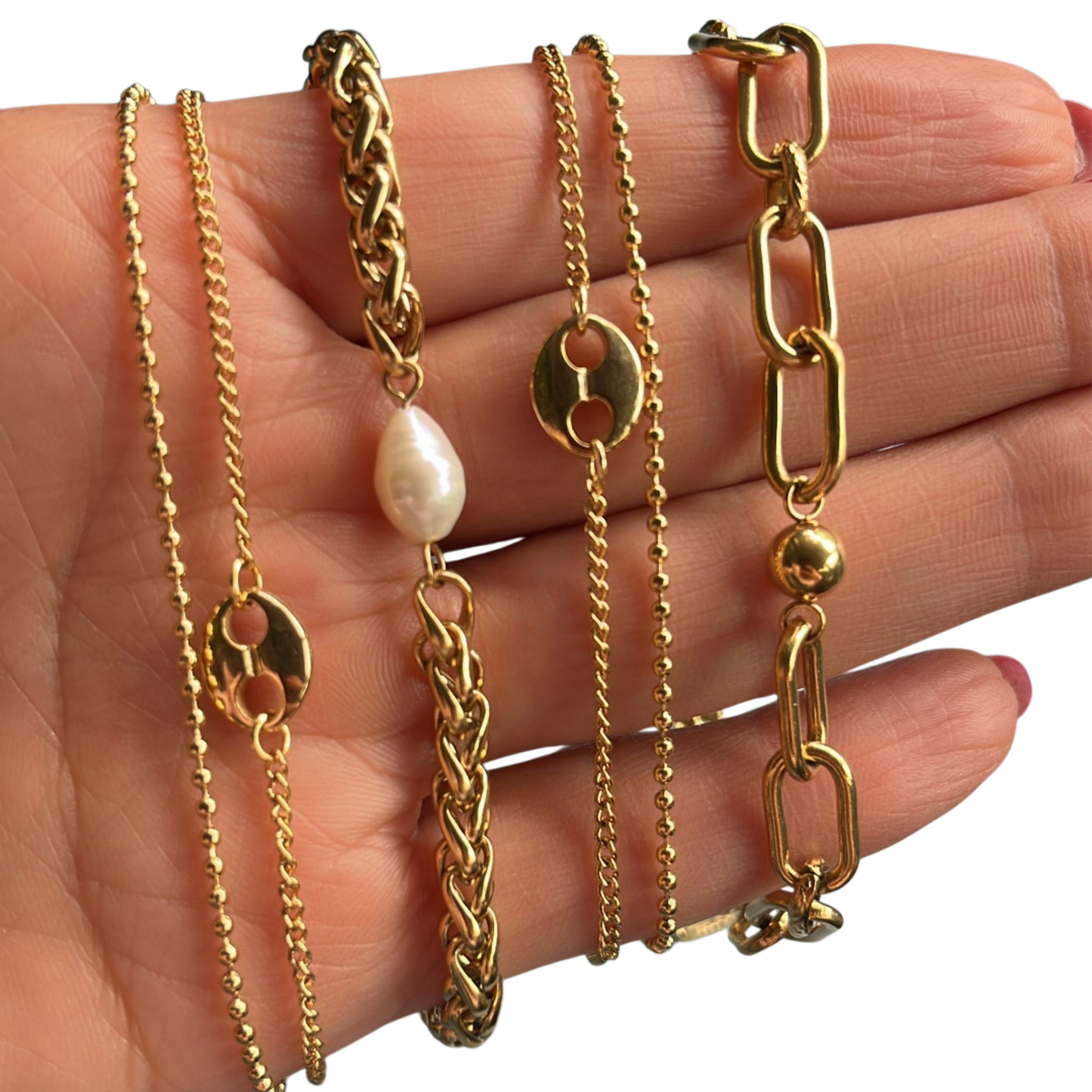 “Pulsera dorada de eslabones con esferas decorativas, exhibida sobre cojín negro. Diseño elegante”